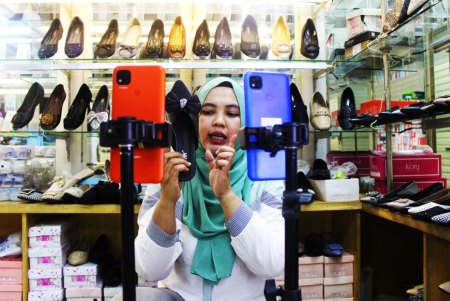 Seorang pedagang sepatu berjualan secara daring di tokonya di Pasar Tanah Abang, Jakarta. (ft antara)