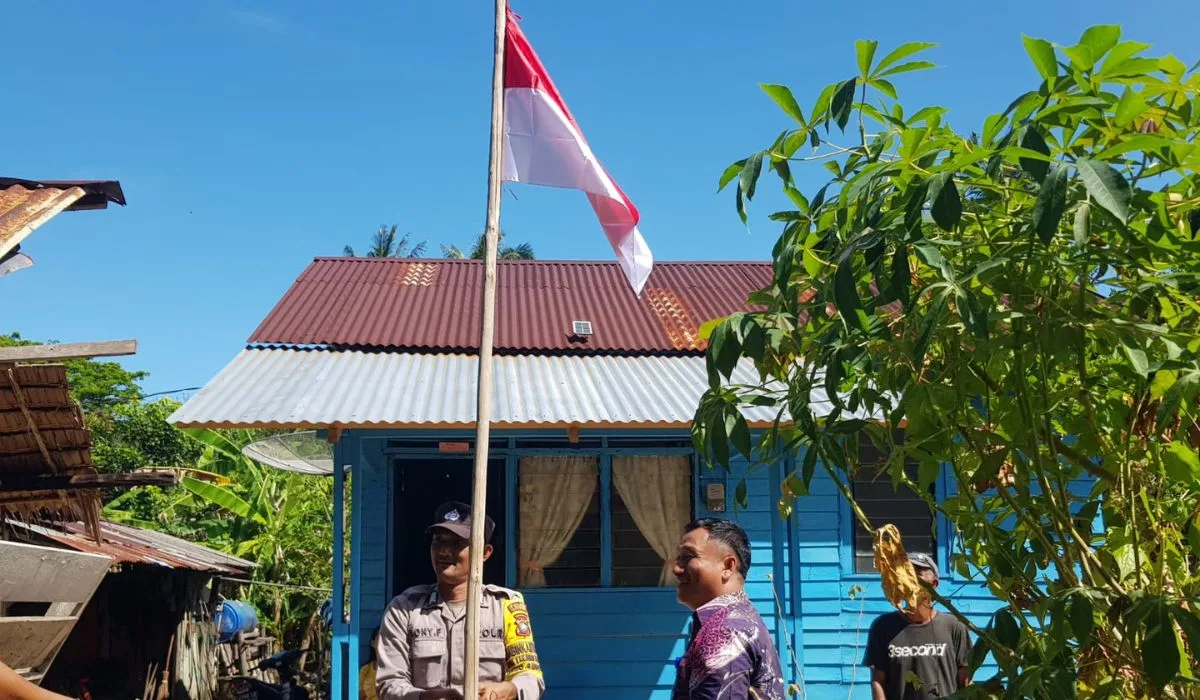 Kades dibantu Bhabinkamtibas Desa Tanjung Harapan melakukan pemasangan bendera merah putih untuk warga, pagi tadi. (ft fuji)