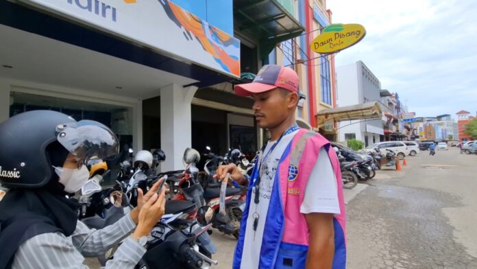 Seorang pengendara saat menunjukkan bukti parkir berlangganan kepada juru parkir di Batam, belum lama ini. (ft alurnews)