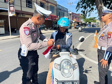 Anggota Polantas Polres Karimun saat membagikan bendera ke pengendara, pagi tadi. (ft novel)