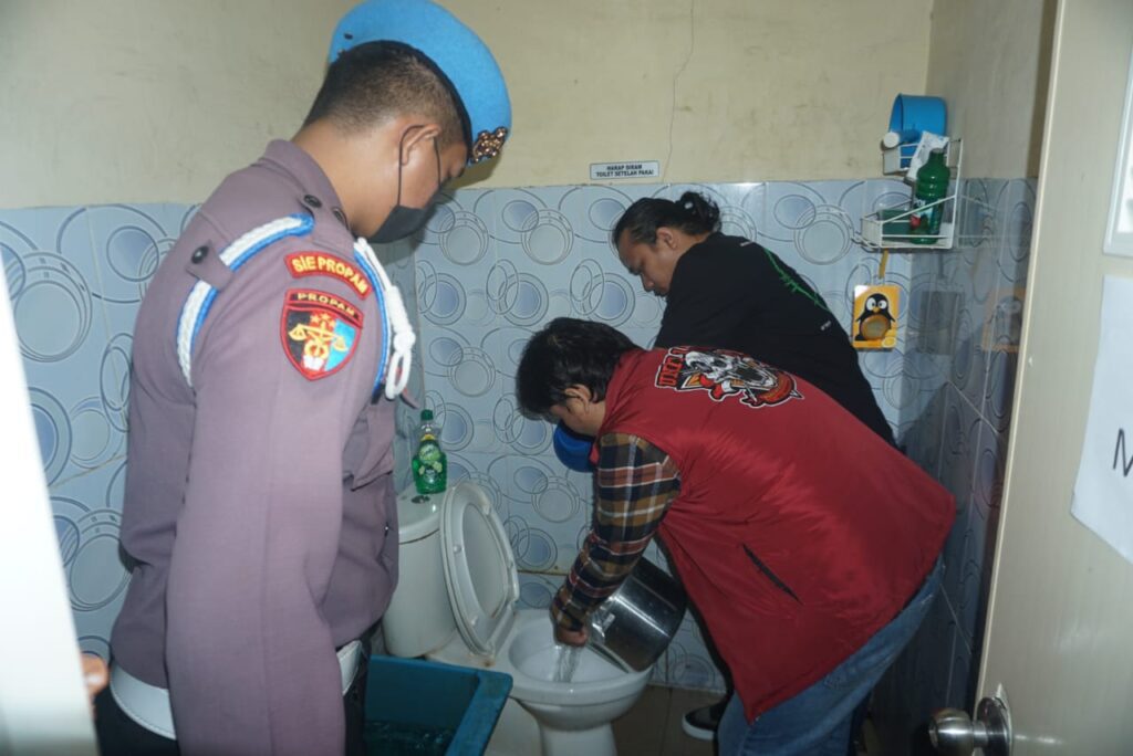 Polisi saat menyiramkan sabu yang sudah direndam ke kloset, siang tadi. (ft humasporleskarimun)