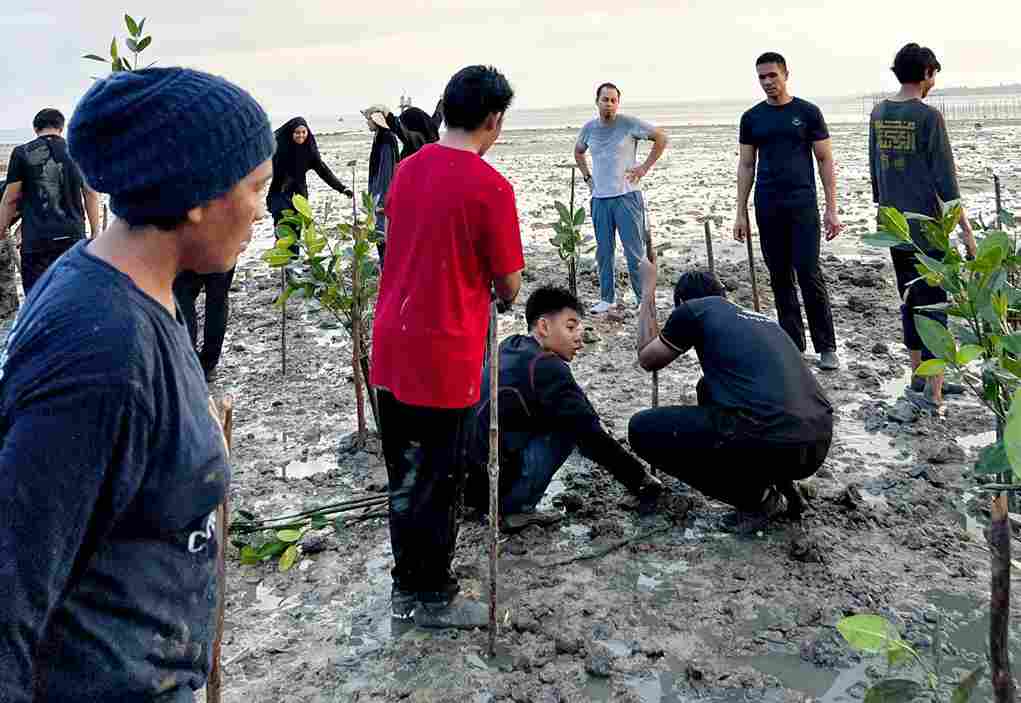 Siswa Singapura dan warga di sela kunjungan wisatanya menanam bakau, kemarin. (ft kominfotpi)