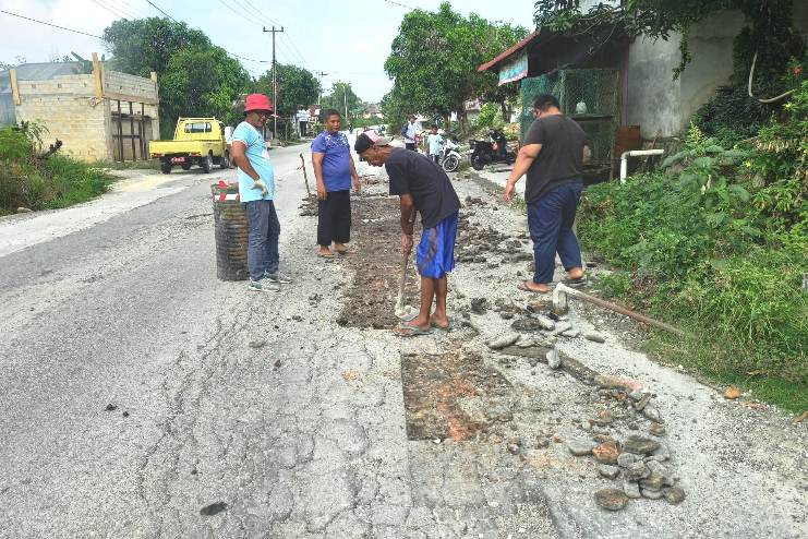 Warga Jelutung saat gotong royong menambal jalan berlubang. Minggu pagi tadi. (ft win)