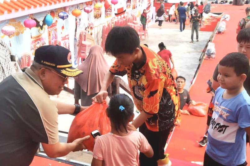 Sekdakab Muhammad Firmansyah saat memabgikan Sembako di Vihara Ngo Hu Niu Niu, Meral, pagi tadi. (ft kominfokarimun)