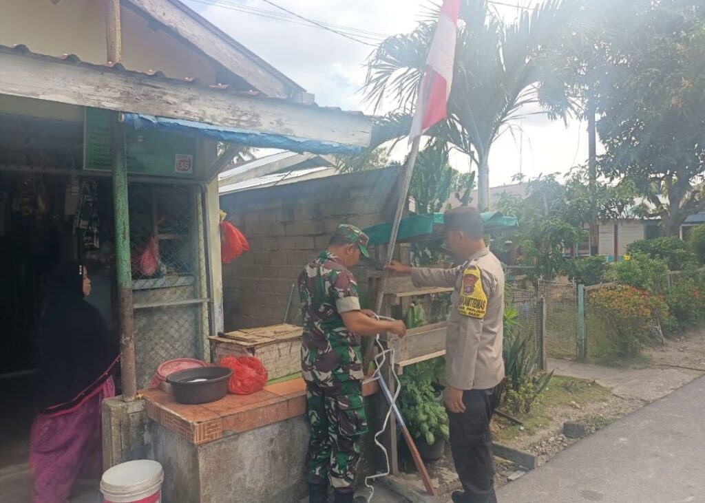 Babinsa dan Bhabinkamtibmas Kelurahan Pasir Panjang saat memasangkan bendera di rumah warga, siang tadi. (ft msaimi)