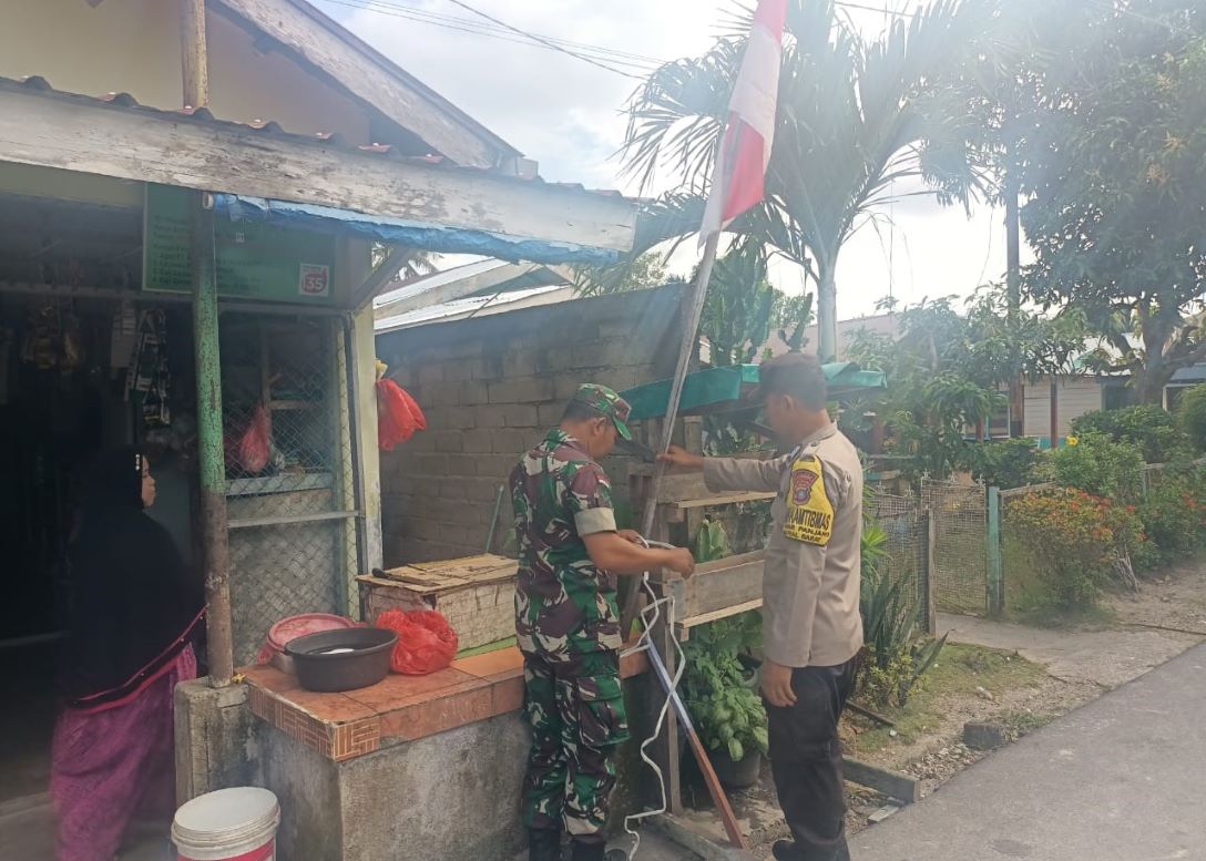 Babinsa dan Bhabinkamtibmas Kelurahan Pasir Panjang saat memasangkan bendera di rumah warga, siang tadi. (ft msaimi)