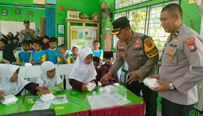 Jajaran Polres Karimun saat membagikan makanan dan susu gratis di SDN 11 Tebing, kemarin. (ft polsektebing)