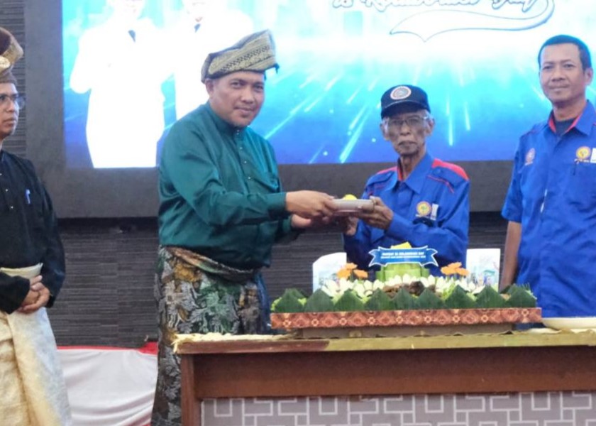 Wabup Karimun menyerahkan potongan tumpeng ke salah satu buruh Karimun, kemarin. (ft prokopim)