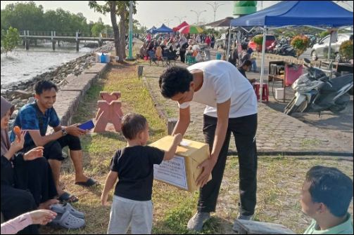 Seorang bocah saat menyerahkan donasi kepada seorang relawan di Coastal Area, belum lama ini. (ft msaimi)